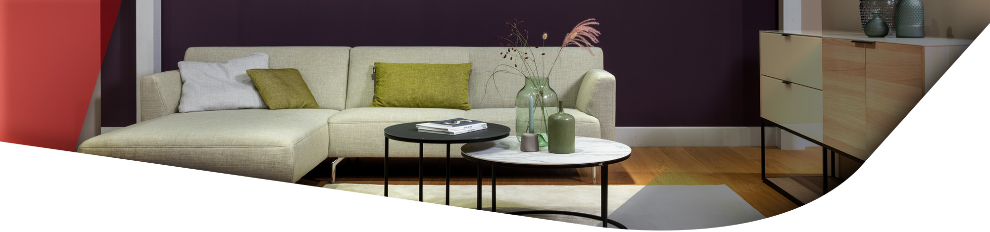 Weiße Couch mit grünen Kissen und runden Couchtischen