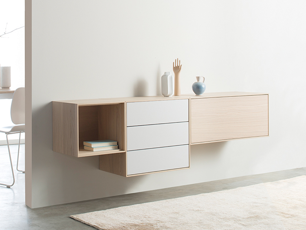 Sudbrock Game - Hängesideboard | Eiche milk furniert, Lack steingrau | B: 200 cm Modernes hängendes Sideboard aus Holz, kombiniert mit weißen Schubladen, dekoriert mit Vasen und einem Holzobjekt auf einer hellen Wand