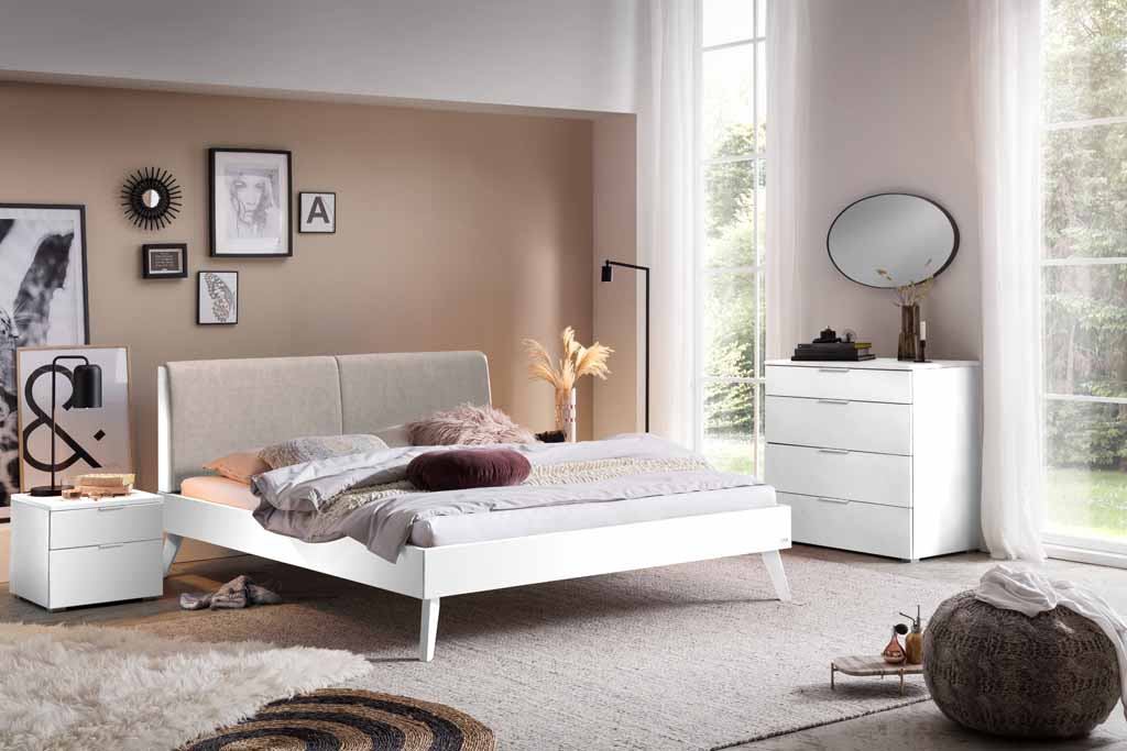 Helles und gemütliches Schlafzimmer mit Doppelbett, Nachttisch, Kommode und dekorativer Wandkunst